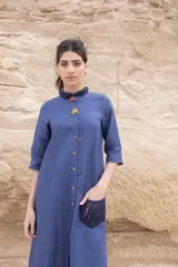Vestido camisero azul de largo midi, con cuello mao con volados y mangas 3/4. Tiene cierre frontal con botones y un bolsillo de crochet aplicado.