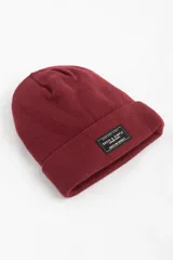 Gorro de punto color burdeos con parche en el frente, confeccionado en acrílico.