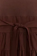Vestido midi marrón con cuello barco y manga sisa. Presenta un corte a la altura de la cintura con detalle de trabilla y lazo del mismo tejido. Cierre lateral con cremallera oculta.