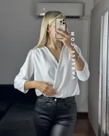 Blusa negra con estampado de lunares blancos, escote en V cruzado, mangas 3/4 abullonadas y hombreras. Talle único abarca hasta L.