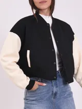 Campera bomber de corte clásico en negro y blanco, con cierre frontal y bolsillos laterales.