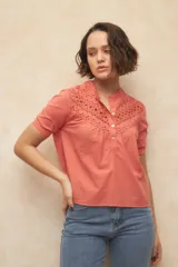 Blusa coral de corte suelto, con detalles de encaje en el frente y cuello tipo mao.