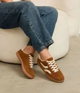 Championes de estilo chuteira, color marrón con recortes y detalles en color crema. Presentan cordones blancos y suela baja de goma color caramelo.