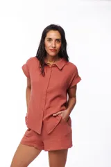 Camisa color ladrillo de algodón con cuello clásico, manga corta con dobladillo y cierre frontal con botones.