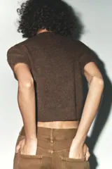 Sweater marrón de tejido de punto con cuello redondo y mangas cortas. Presenta apliques florales tejidos al crochet en el frente.