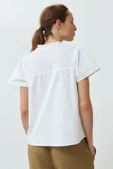 Blusa blanca con punto smock en el cuello, manga corta y cierre con botones.