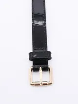 Cinto negro de charol con hebilla dorada rectangular.