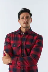 Sobrecamisa de algodón para hombre con interior de corderito, estampado a cuadros en tonos negro, blanco y azul. Tiene cierre de botones, bolsillos tipo cartera y logo en goma. El modelo usa talle M.