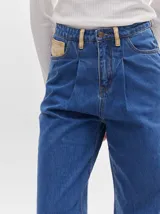 Pantalón de denim color marrón claro, de tiro alto, corte amplio y pinzas en la cintura.