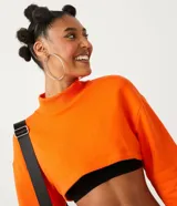 Buzo cropped blanco de algodón con cuello alto y puños acanalados.