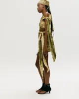 Conjunto de top y falda corta con estampado abstracto en tonos beige y verde. El top es de un solo hombro con abertura en el abdomen y la falda es cruzada con lazo lateral.