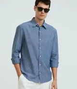 Camisa celeste de lino con cuello camisero, abotonadura frontal y mangas largas.