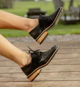 Zapato acordonado de cuero vacuno color marrón oscuro, con suela de goma, horma cuadrada y tacón bajo.