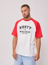 Remera azul marino con mangas raglán color crema y estampado frontal con el logo de Rusty en blanco.