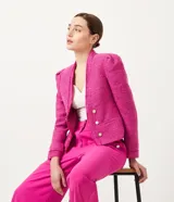 Chaqueta corta de tweed color fucsia, con manga abullonada, cuello mao y cierre frontal con botones perlados.