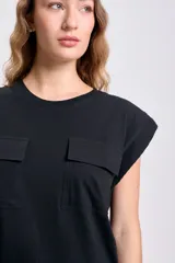 Remera negra de manga corta con cuello redondo y dos bolsillos cuadrados en el pecho.