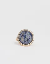 Anillo dorado con piedra redonda azul con manchas grises.