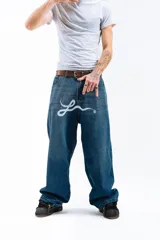 Pantalón de jean azul desgastado, corte mega baggy, con estampa serigrafiada en la pierna y botones personalizados.