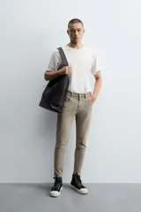 Pantalón de jean color beige, corte skinny, tiro medio, largo cropped y cinco bolsillos.