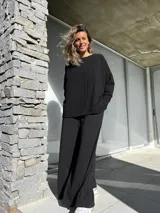 Conjunto negro compuesto por un remerón oversize de mangas largas y un pantalón palazzo de tiro alto con elástico en la cintura.
