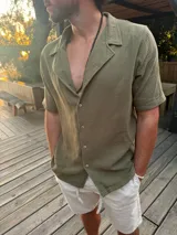 Camisa verde militar de muselina con cuello solapa, manga corta y cierre frontal con botones.
