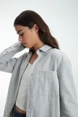 Camisa de algodón gris melange con diseño clásico, botones frontales y un bolsillo en el pecho.
