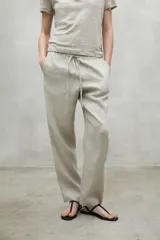 Pantalón de lino color beige, de corte recto, con cintura elástica ajustable con cordón y bolsillos laterales.