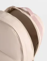 Mochila color beige de tela deportiva con textura. Tiene correa regulable, manija superior, cierre superior, doble bolsillo frontal con cierre y pullers, y bolsillos laterales.