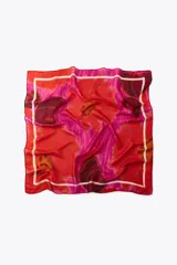 Pañuelo cuadrado de modal y seda con estampado de amapolas en tonos rojos y fucsias, y borde blanco.