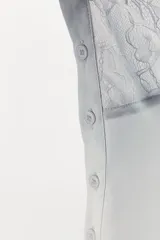 Top blanco de escote recto y tirantes finos, con detalle de costuras marcadas y aplicación de encaje floral combinado a tono.