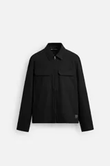 Sobrecamisa negra relaxed fit confeccionada en tejido con mezcla de algodón. Cuello solapa y manga larga acabada en puño con botones a presión. Bolsillos de plastrón con solapa en pecho y laterales en costura de cadera. Cierre frontal con cremallera.