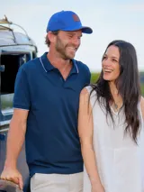 Remera tipo polo color beige, de corte clásico, con cuello y puños acanalados en contraste marrón oscuro.