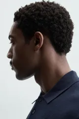 Polo azul marino de punto ligero tejido en hilatura con mezcla de seda y algodón. Cuello solapa con cierre frontal de botonadura, manga larga y acabados en rib.