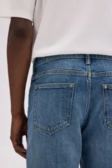 Pantalón de jean azul de corte recto, con cinco bolsillos y cierre con botón y cremallera.