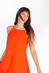 Vestido corto color naranja, con escote halter y diseño asimétrico con capas. Espalda con tiras regulables.