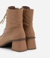 Bota de cuero color marrón claro, de caña media, con puntera cuadrada, taco bloque y cierre con cordones y cremallera.