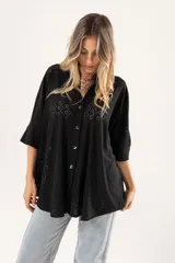 Camisa negra con calados, escote en V, abotonada y manga 3/4.