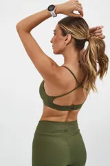 Top deportivo color beige con banda inferior azul y tirantes finos azul marino. Espalda cruzada con doble tira.