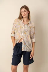 Camisa de dama estampada con flores amarillas y lilas sobre fondo beige, de corte clásico y mangas largas con puños abotonados.