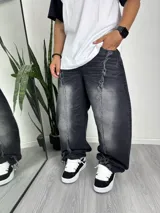 Pantalón de jean negro con efecto lavado, corte ancho y detalles rotos en los laterales.