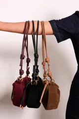 Cartera tipo sobre color bordó, confeccionada en PU tipo gamuza, con correa regulable de nudos chunky y cierre superior.