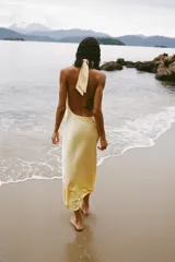 Vestido midi de satén color amarillo pálido, con cuello halter y espalda descubierta.