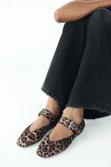 Zapato plano tipo bailarina con estampado animal, tira sobre el empeine con hebilla metálica y punta redondeada.