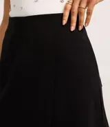 Short pollera negro de crepé con diseño cruzado, bolsillos traseros y pinzas.