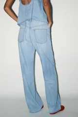 Pantalón denim celeste de tiro medio con cintura ajustable con cordones, bolsillos laterales y de plastrón en espalda. Cierre frontal con cremallera y gancho metálico.