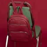 Mochila bordeaux de símil cuero con cierres metálicos, doble bolsillo frontal, asa de mano y correas regulables en galón.