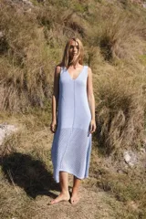 Vestido tejido de punto color celeste claro, largo midi, con escote en V y sisas profundas. La parte inferior presenta un calado en patrón de rombos.