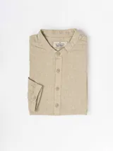 Camisa de lino color beige, de manga larga y cuello mao, con cierre frontal de botones.