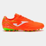 Championes de fútbol Joma modelo Aguila, color naranja vibrante con detalles en blanco y verde neón. Presentan un diseño clásico con costuras en la puntera y tacos moldeados para césped natural o artificial.