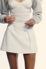 Falda pantalón blanca de tiro medio, con corte ligeramente acampanado y detalle de cinturón fino con hebilla metálica.